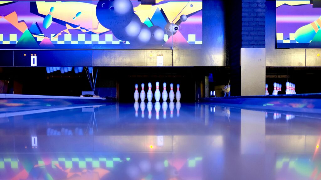Colorful bowling alley with pins and reflections under neon lights.