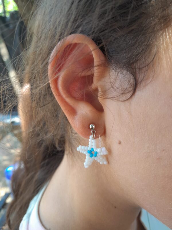 Pendientes veraniegos hechos de manera artesanal con delicadas cuentas en forma de estrella en colores azul celeste y blanco.