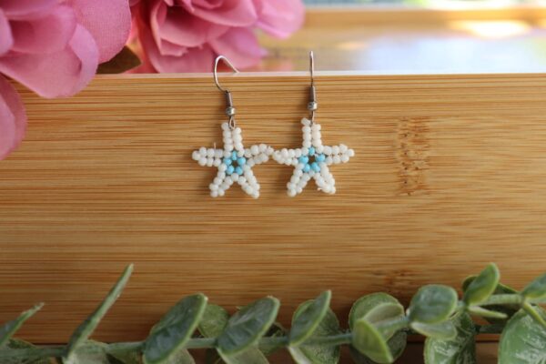 Pendientes veraniegos hechos de manera artesanal con delicadas cuentas en forma de estrella en colores azul celeste y blanco.
